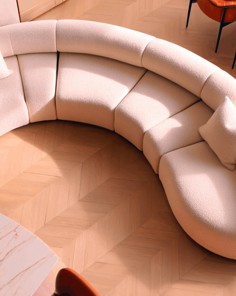 curved sofa in a light coral color on a hardwood floor